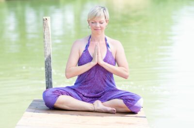 Yoga im Sommer: Yogini im Meditationssitz im Sommer am See
